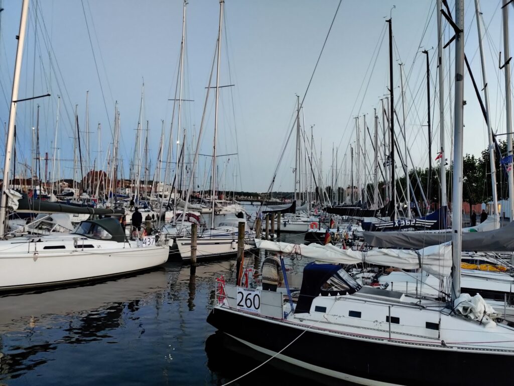 Dicht aneinandergereihte Segelboote im Yachthafen; unzählige Masten ragen in den abendlichen Himmel.