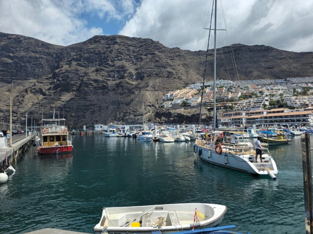 Yachthafen vor steilen Felsbergen; Segel- und Fischerboote, terrassenförmig ansteigende weiße Häuser im Hintergrund